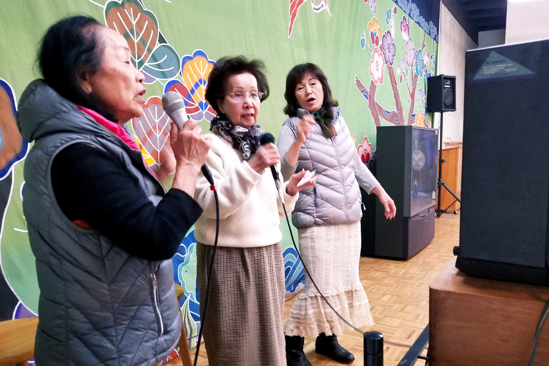 Three women singing into microphones